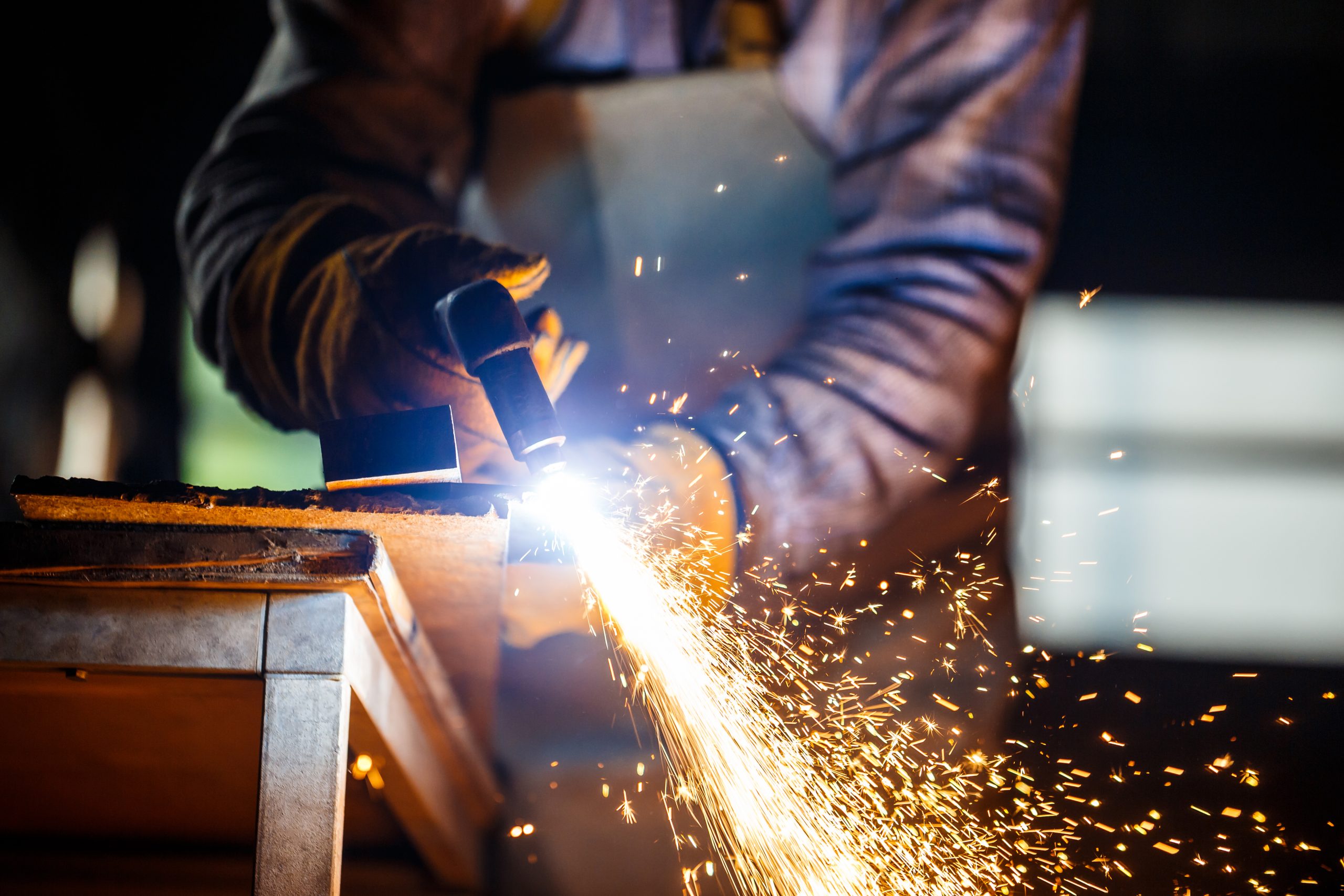Worker cutting metal with plasma equipment on plant.